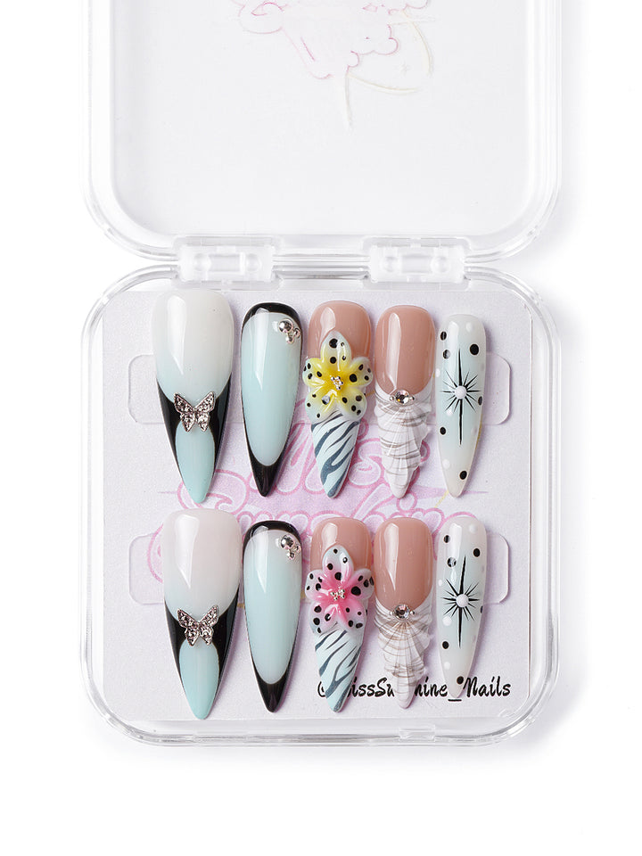 Handmade press-on nails featuring bold prints, rhinestone butterflies, and edgy floral accents
