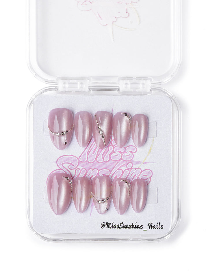 Handmade rosé press-on nails with pearlescent base, chain drapes, and mini studs