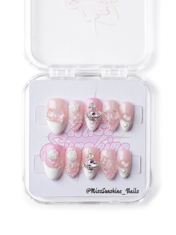 Dreamy pink celestial press-on nails with pearl details, butterfly accents, and a statement planet charm