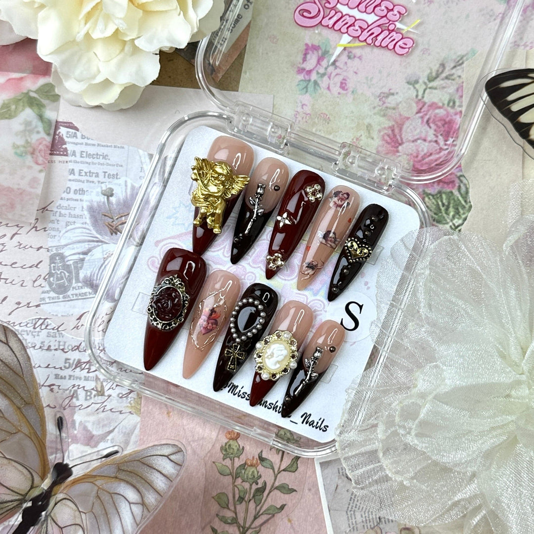 Long stiletto nails with gold cherub and cross details