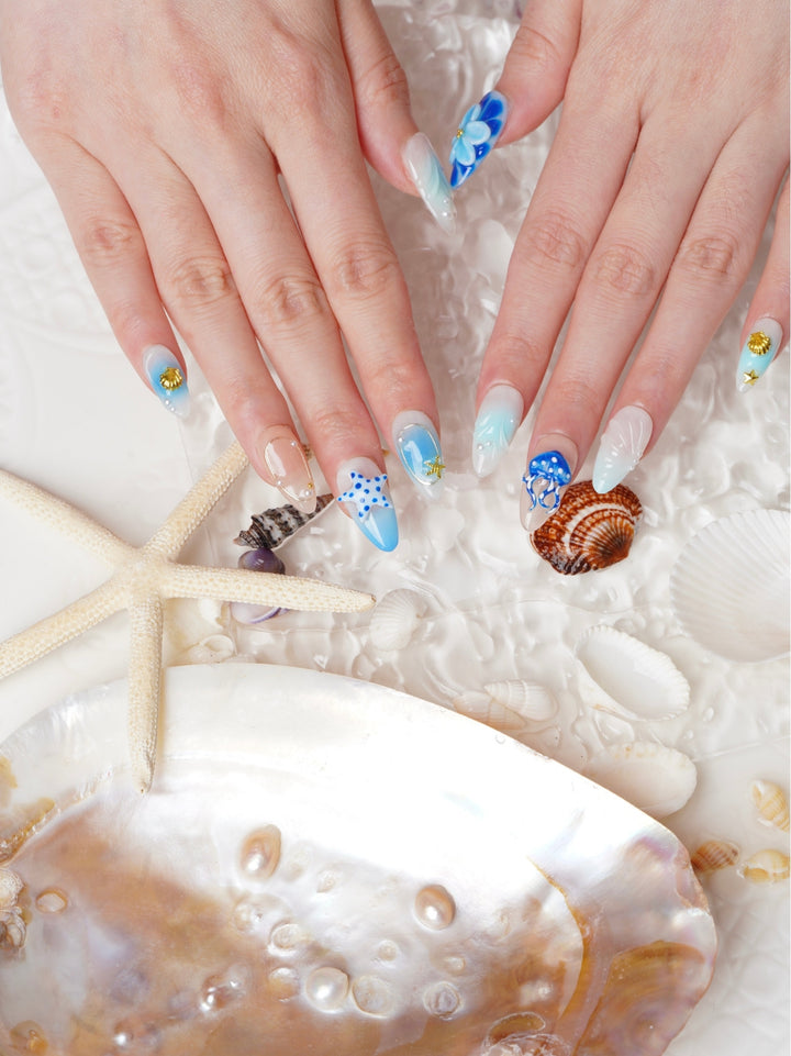 Short almond press-on nails with blue jellyfish art, 3D florals, pearls, and seashell textures