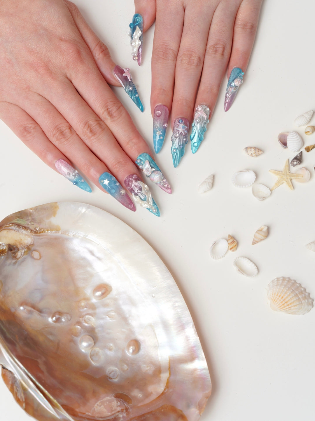 Mermaid-inspired handmade nails featuring metallic ocean textures, glitter finish, and under-the-sea elements