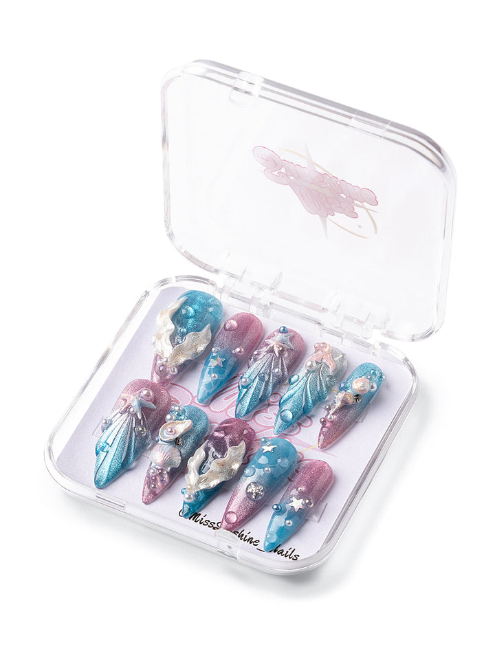 Long stiletto press-on nails with shimmer blue and pink gradients, 3D shells, pearls, and ocean textures