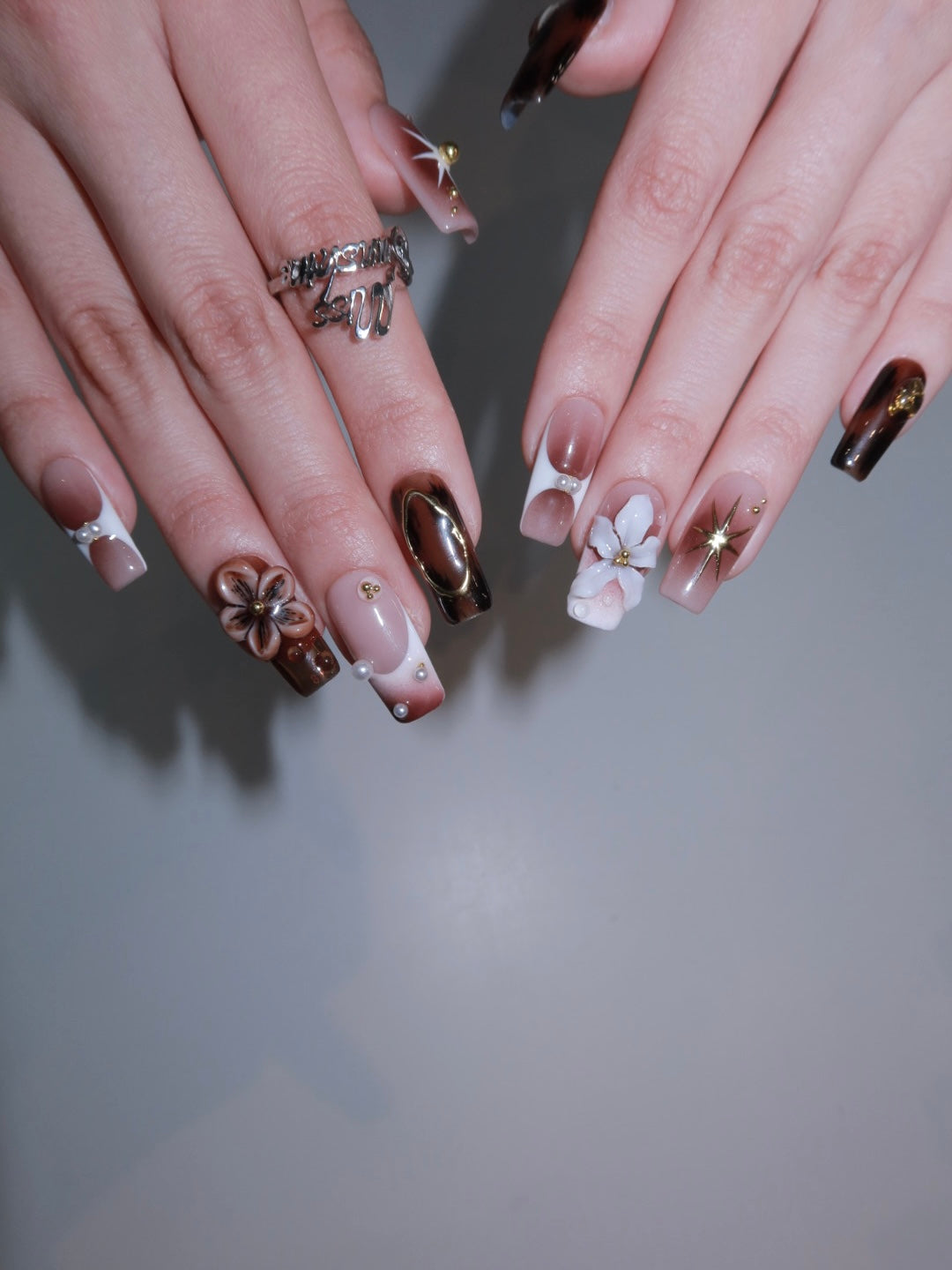 Medium square press-on nails with brown and nude contrast, complete with gold starburst and floral