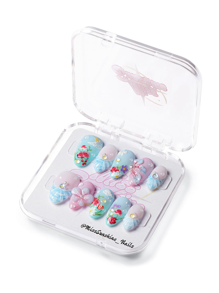 Short almond press-on nails with pastel florals, cloud and moon art, pearls, and soft sky tones