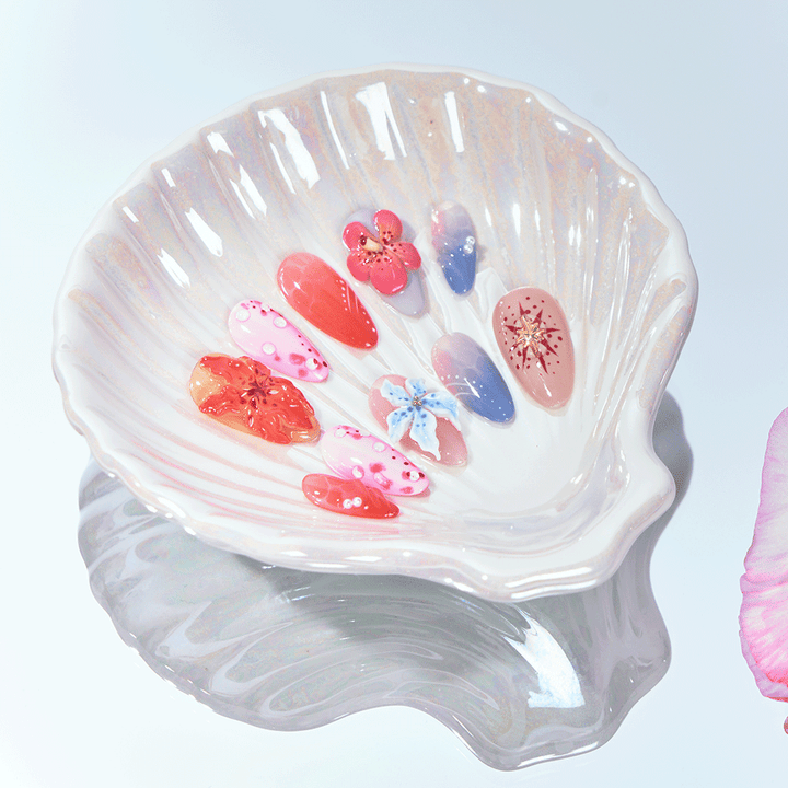 Short almond press-on nails with floral art, coral accents, and ombré summer tones.