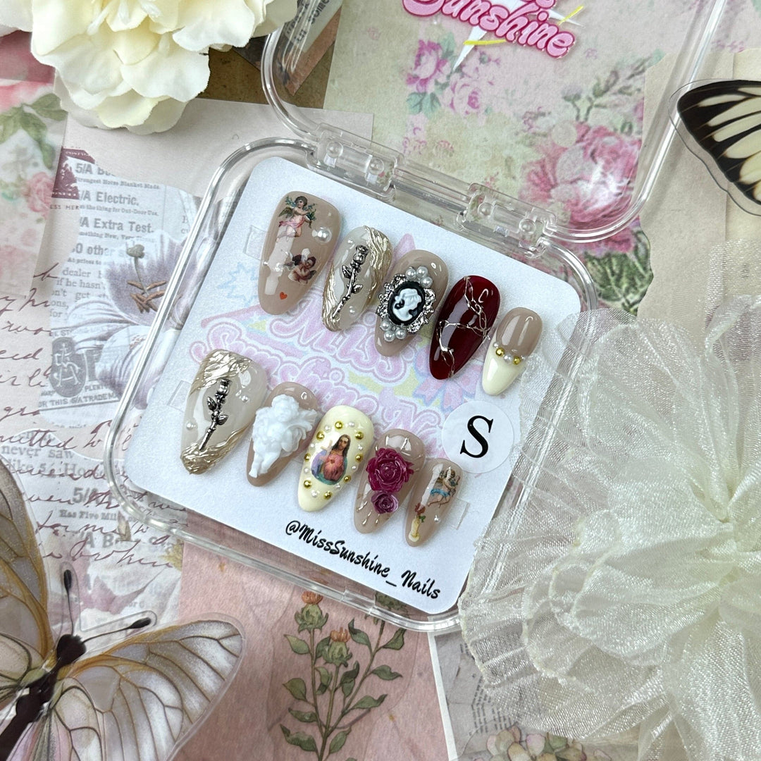 Artistic nail set featuring gold leaves, pearls, and hand-painted portraits on press-ons