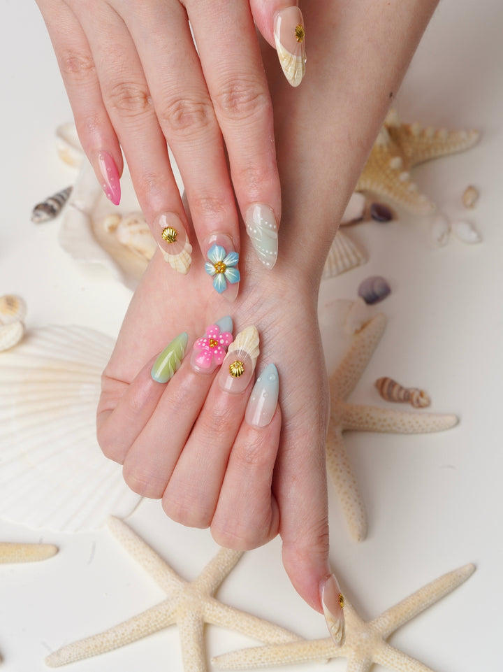 Handmade beach-themed nails featuring polka dots, floral textures, and seashell details
