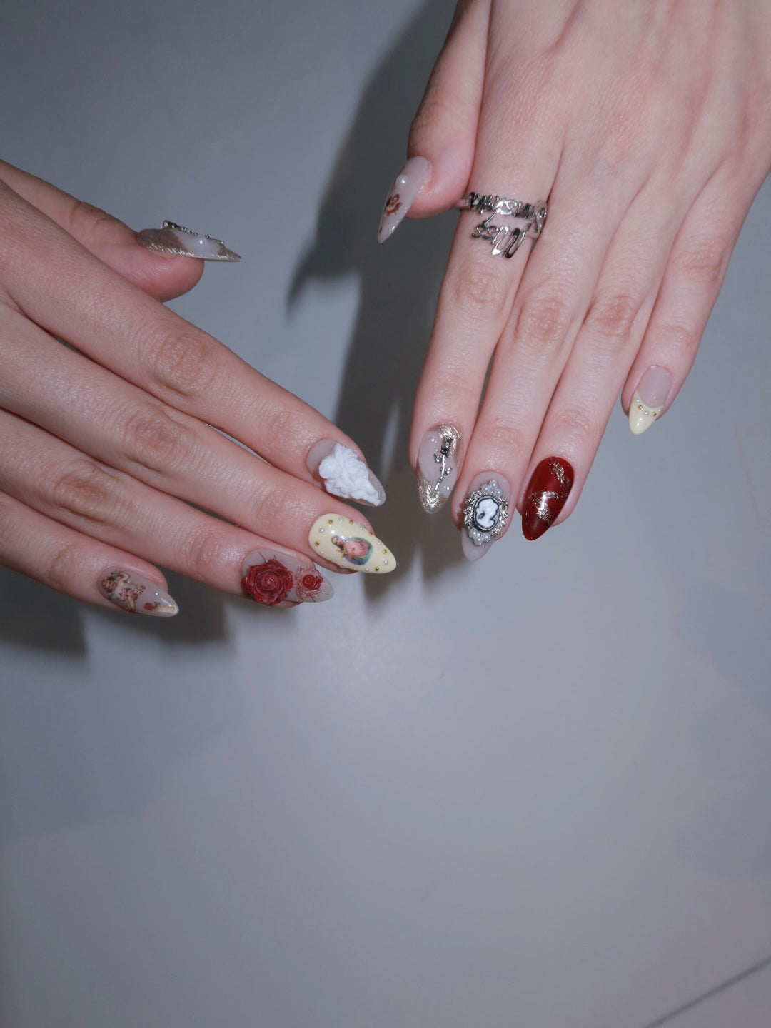 Short almond press-ons with gold foil and baroque angel accents for a vintage romantic look