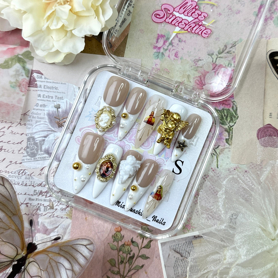 Angel Twins long stiletto press-on nails with 3D angel charms, gold pearls, and classical portraits.