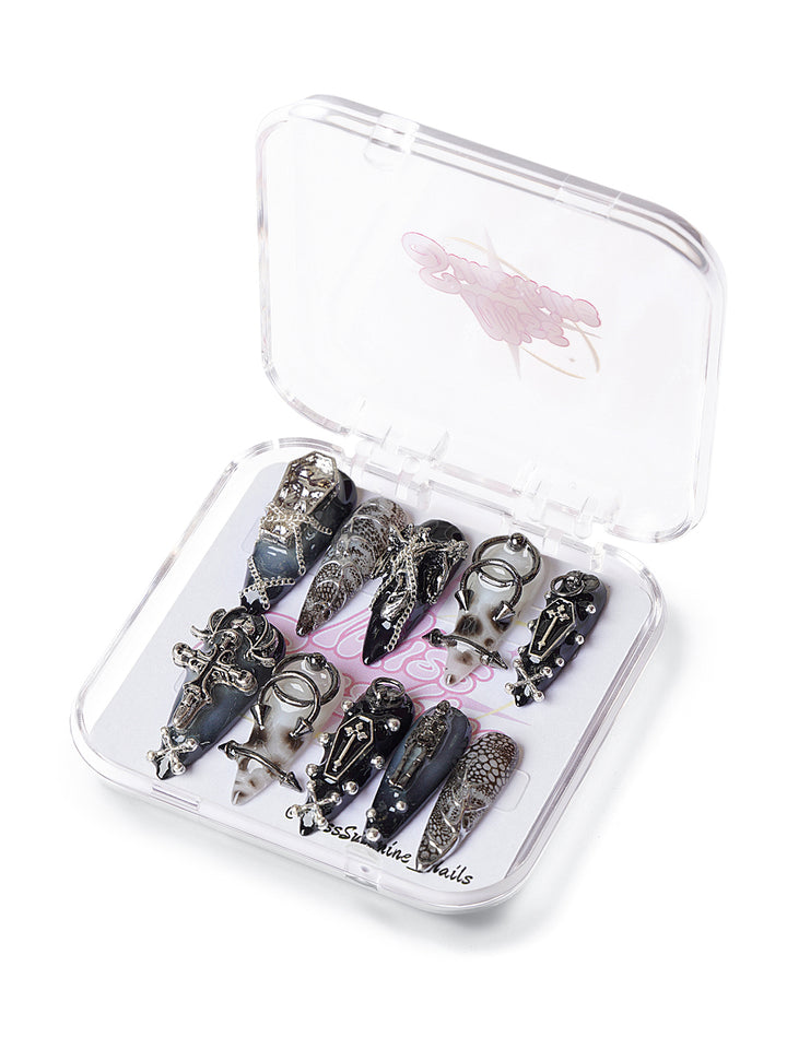 Long stiletto press-on nails with crosses, chains, and coffin accents