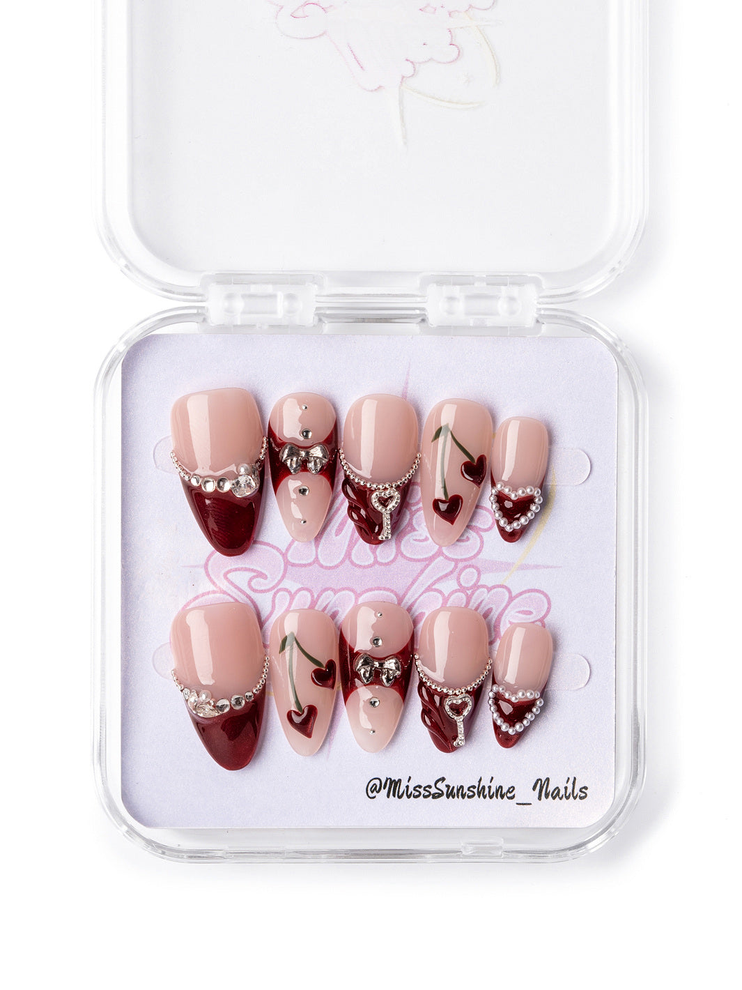 Valentine’s Day press-on nails in cherry red and nude with sparkling rhinestones and heart details.