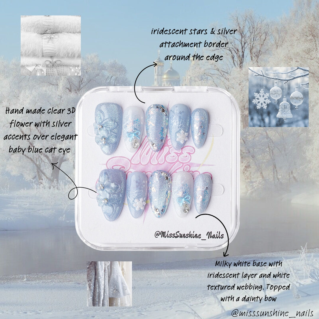 Blue almond-shaped nails with sparkling gradients, crystals, and delicate winter floral designs