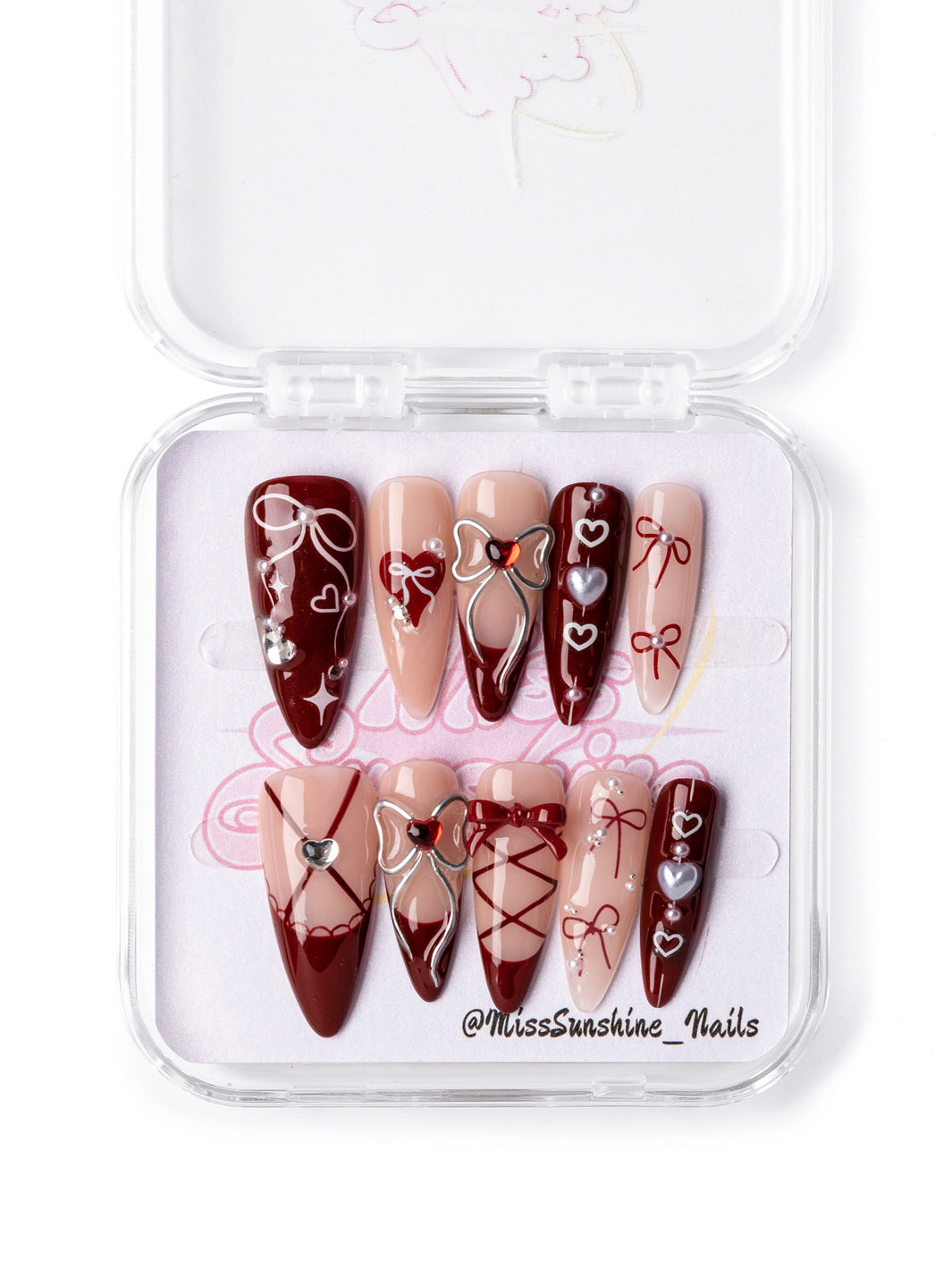 Long almond Valentine’s Day nails in burgundy and nude with elegant lace and bow designs.