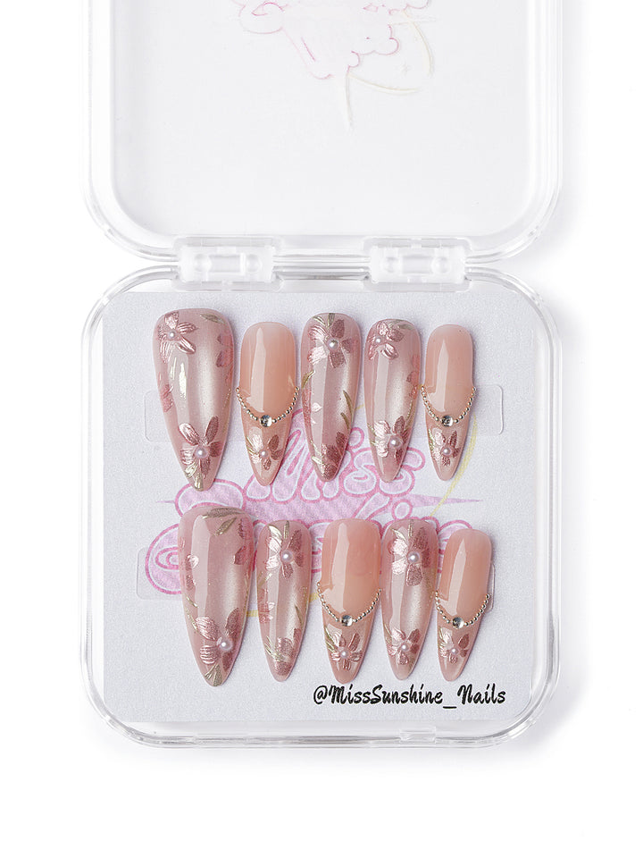 Pink and nude ombré nails with sculpted flowers, gold cross charms, and rhinestones