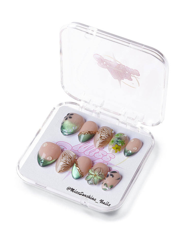 Evergreen extra short almond press-on nails with nude tones, emerald gradients, and gold botanical accents