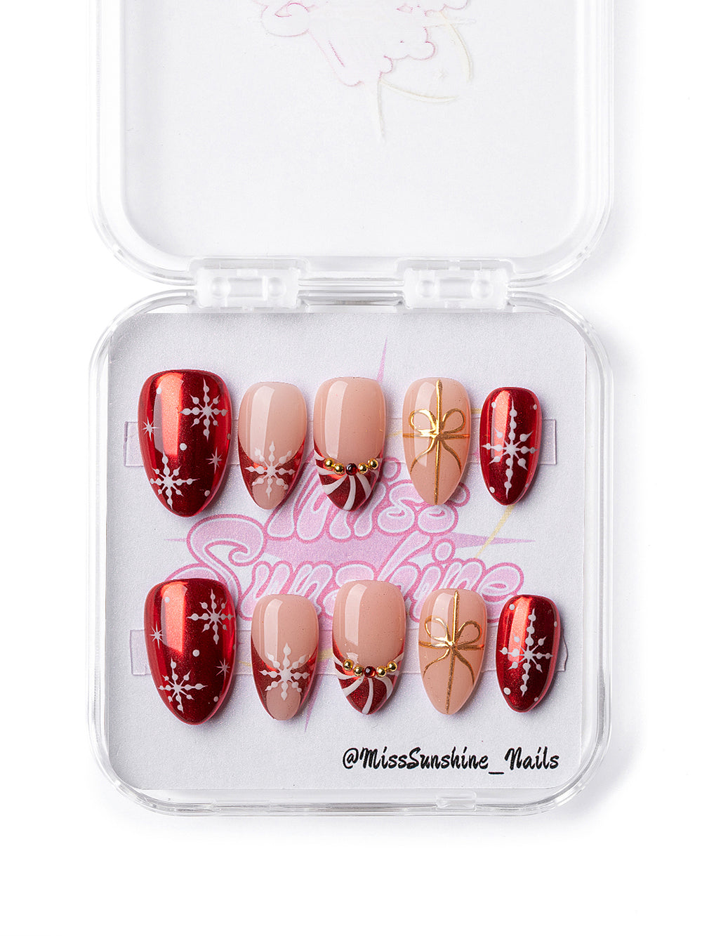 Holiday press-on nails featuring nude and red with gold ribbon accents