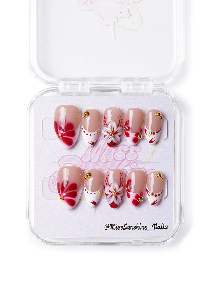 Handmade press-on nails with bold red petals and soft nude base for a chic everyday look