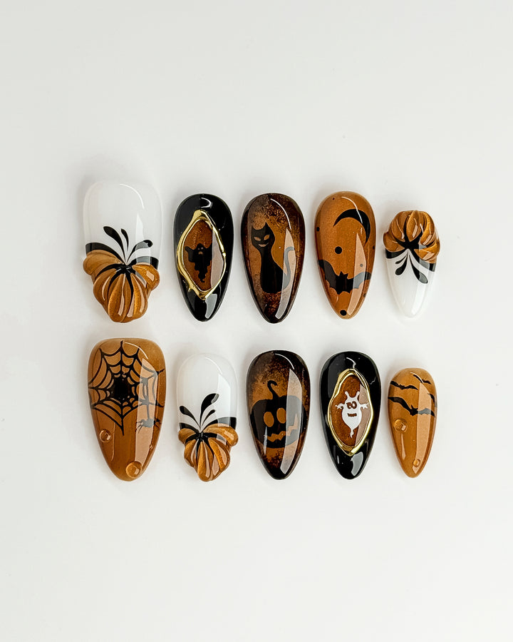 Festive fall press-on nails with spooky pumpkin and bat details by Miss Sunshine NYC.