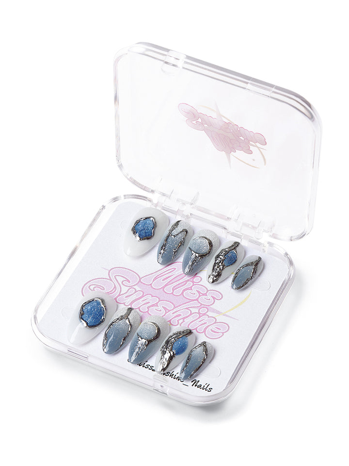 Short almond press-on nails with chrome silver detailing, icy blue gradients, and geode-inspired textures