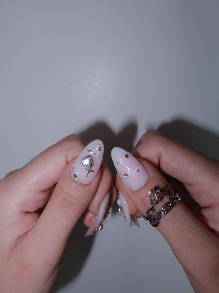 Short almond nails with metallic bows and pearls