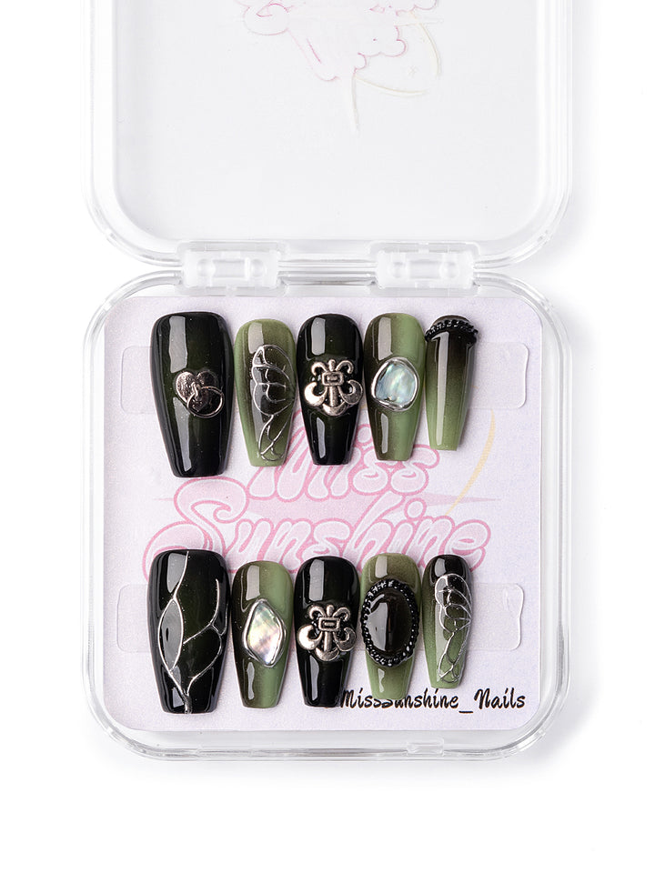 Glossy black nails with metallic bow and shell charms