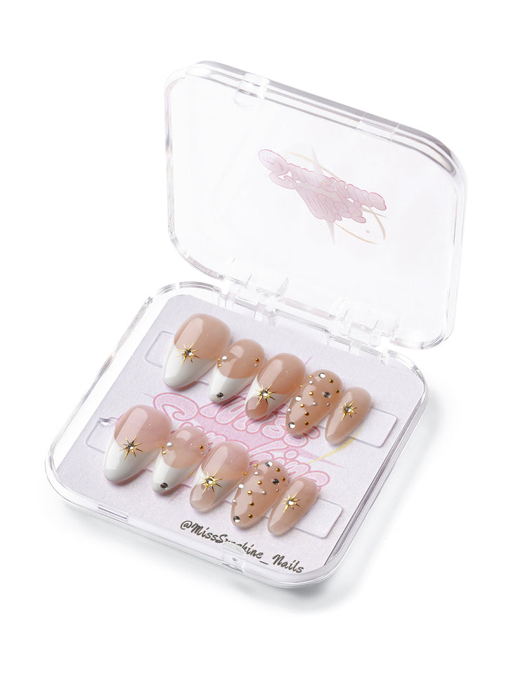 Golden Hour short almond press-on nails with nude tones, gold stars, and crystal accents.
