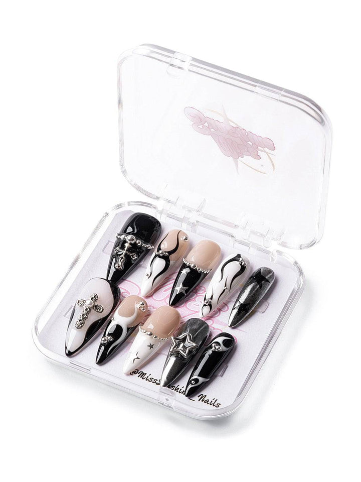Long stiletto press-on nails in black, white, and silver with dramatic cross embellishments