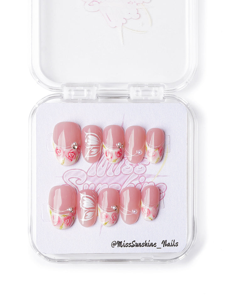 Handmade pink floral nails with butterfly wings and pearls in short oval shape, cottagecore-inspired