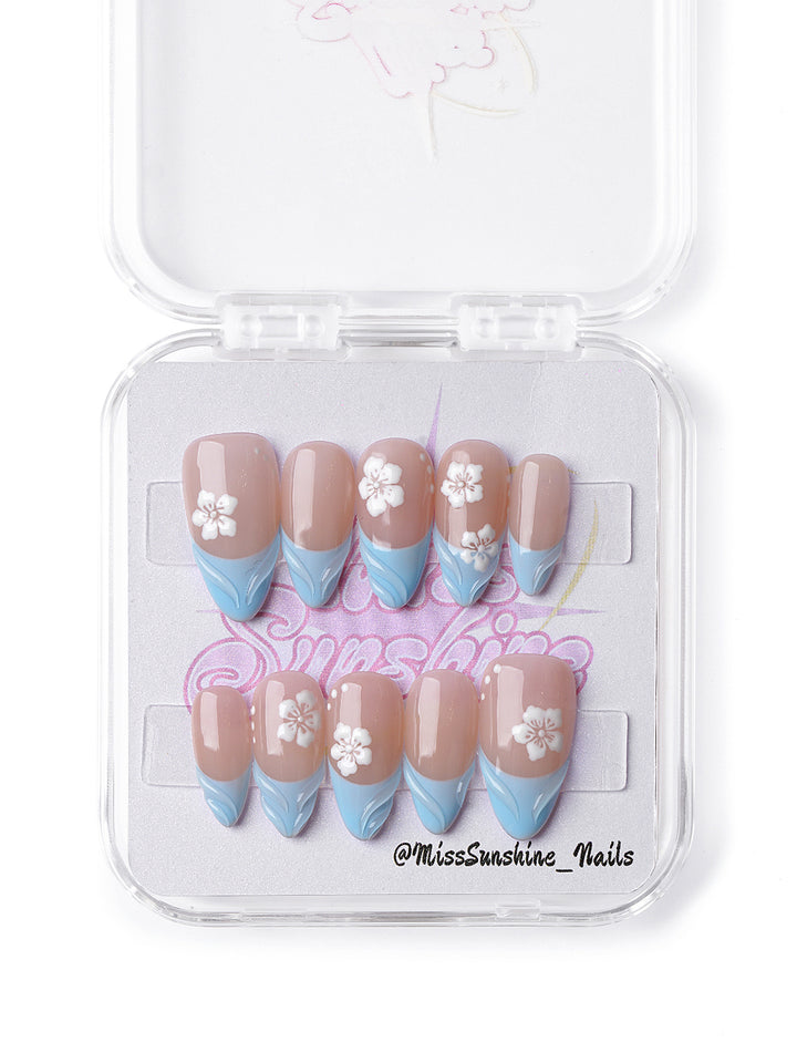  Pastel press-on nails featuring baby blue waves and delicate floral accents.