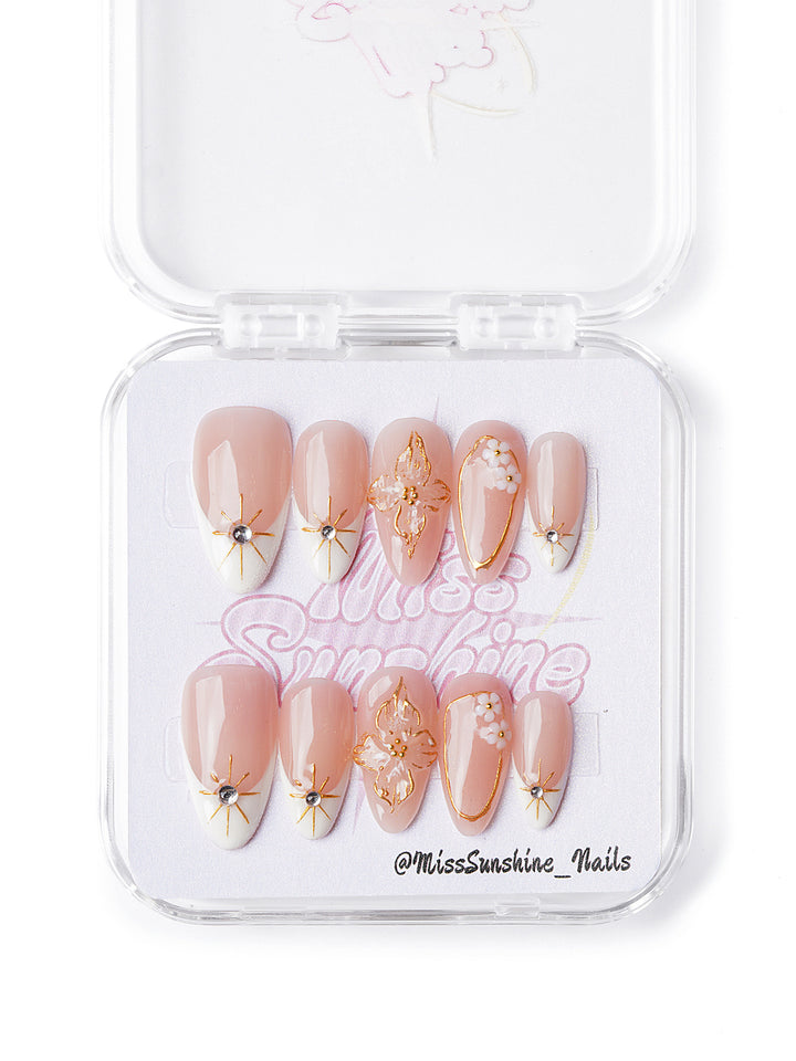 Handmade short almond nails with gold stars, floral tips, and 3D peach and white blossoms