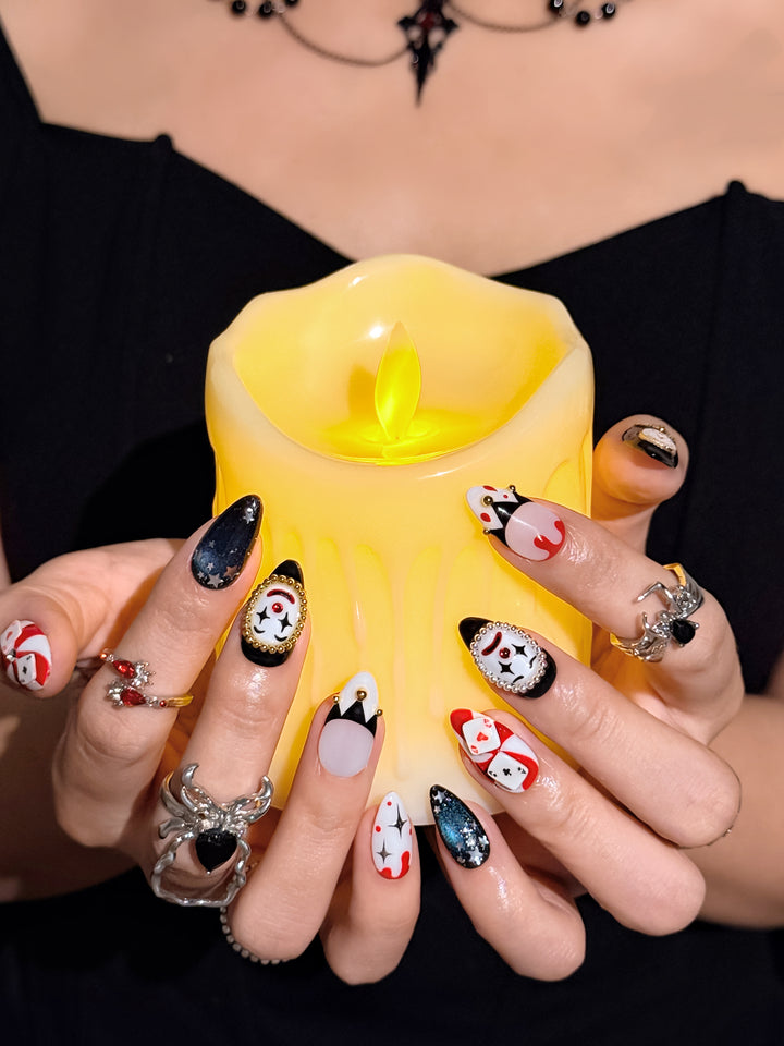 Spooky clown press-on nails with jester details, rhinestones, and red drip nail art