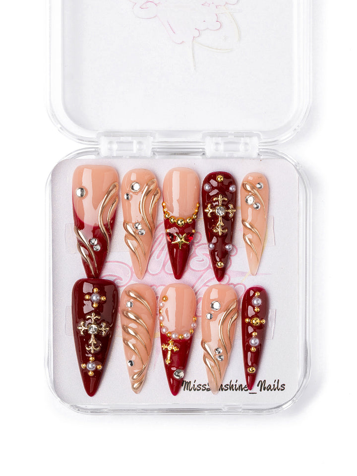 Handmade red and gold almond nails with pearl details and cross charms