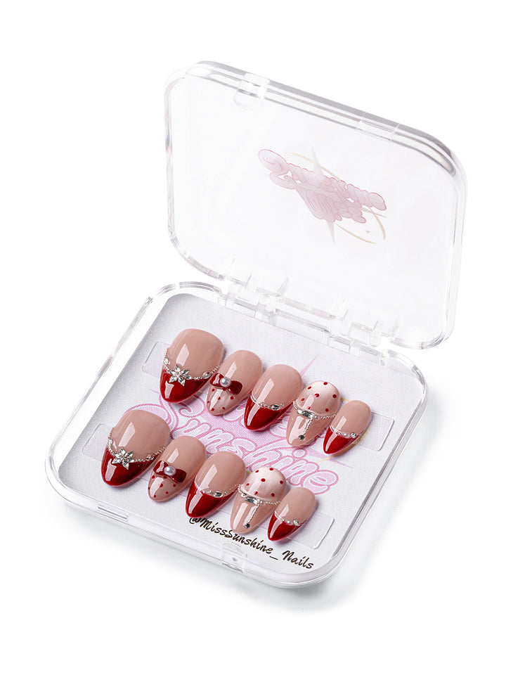 Short almond press-on nails in nude and red with rhinestone accents