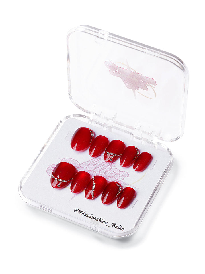 Extra short almond press-on nails in ruby red with rhinestone chain accents and glossy finish
