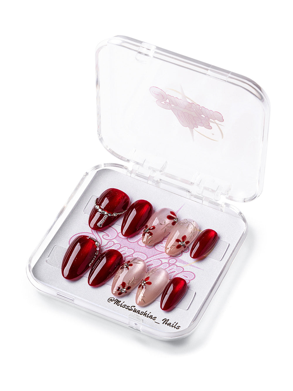 Short almond press-on nails in red and nude with ruby flower accents.