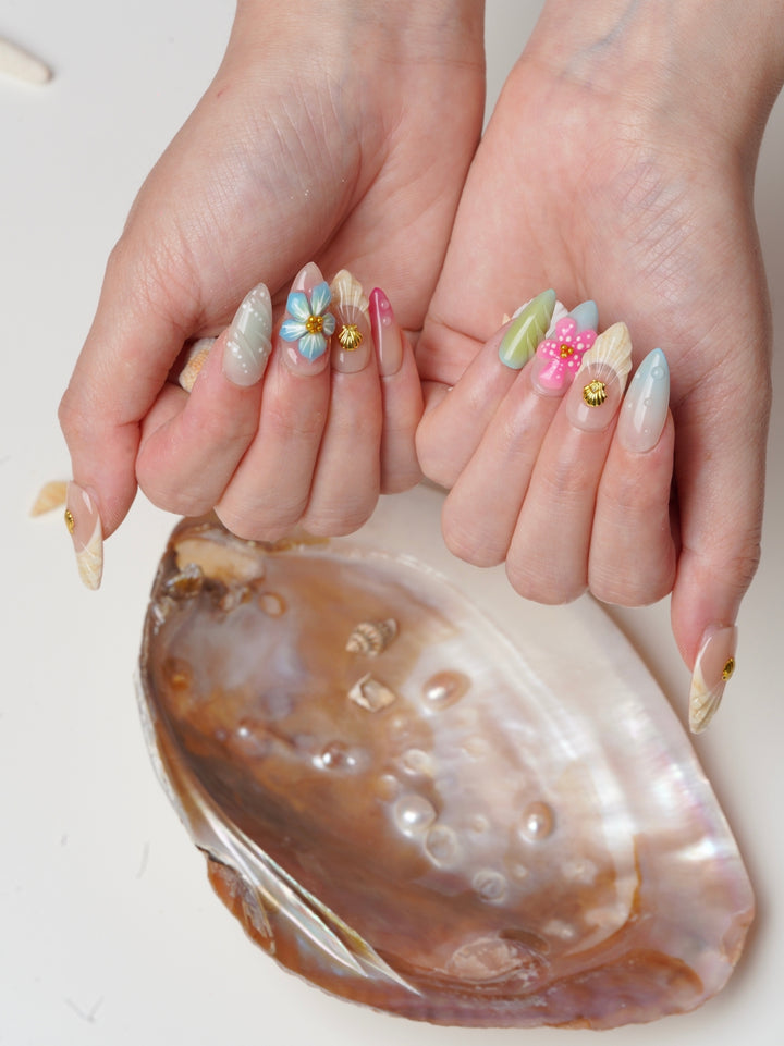 Short almond press-on nails with 3D flowers, gold seashells, and pastel green and pink accents