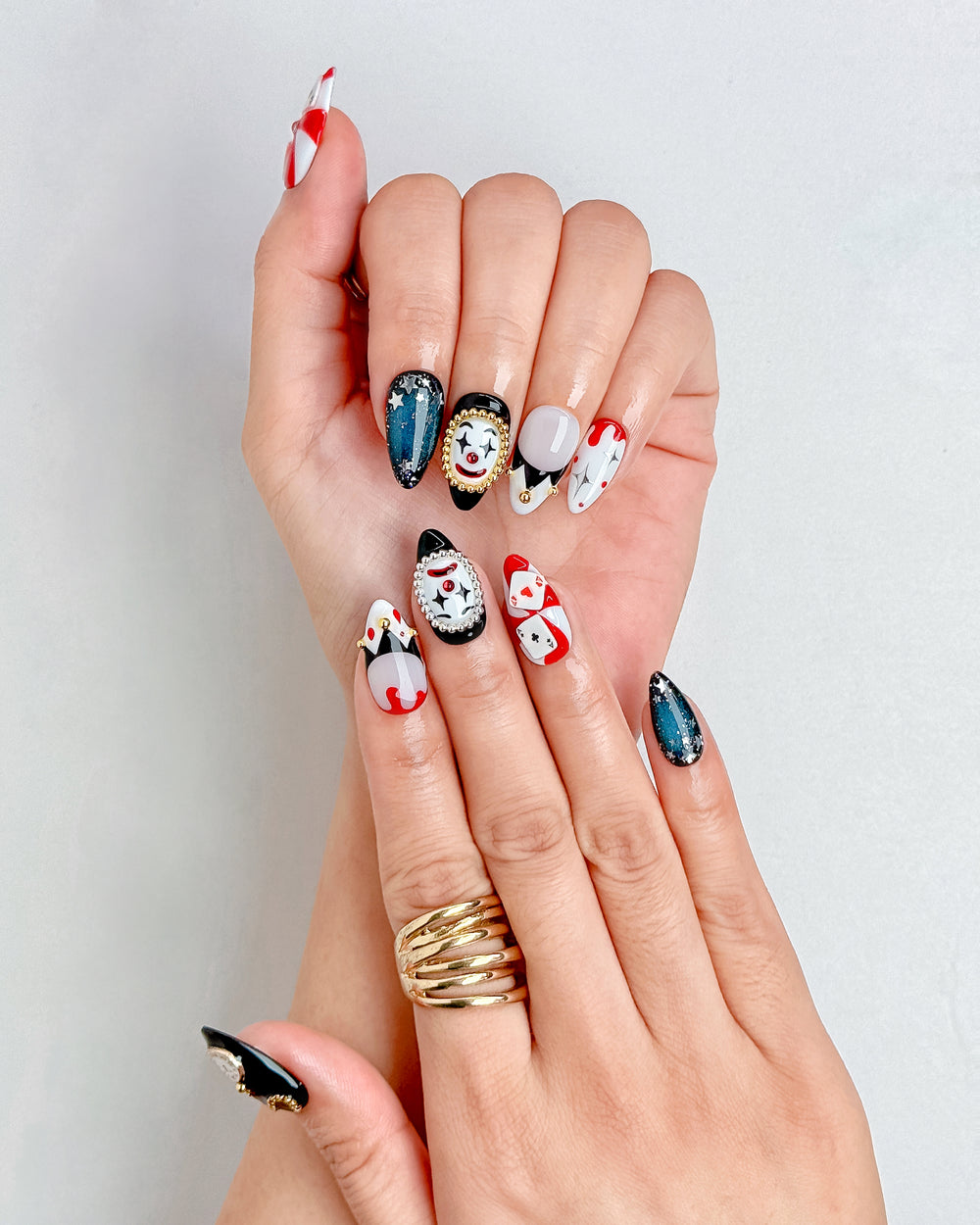 Handmade Halloween nails featuring red poker cards, black glitter, and gold accents