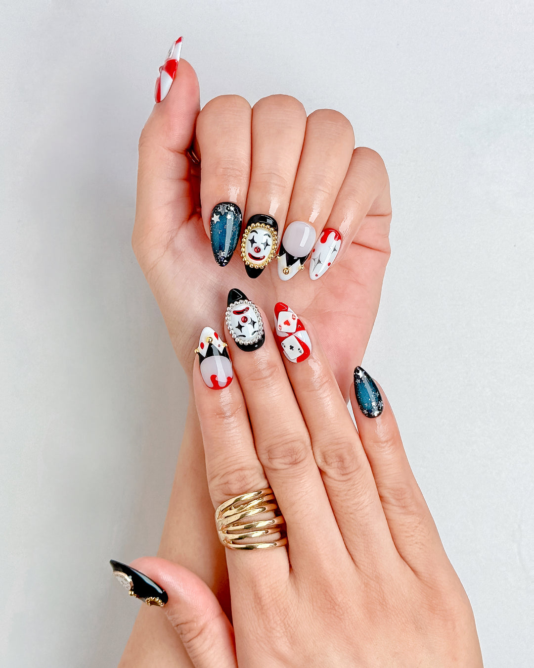 Handmade Halloween nails featuring red poker cards, black glitter, and gold accents