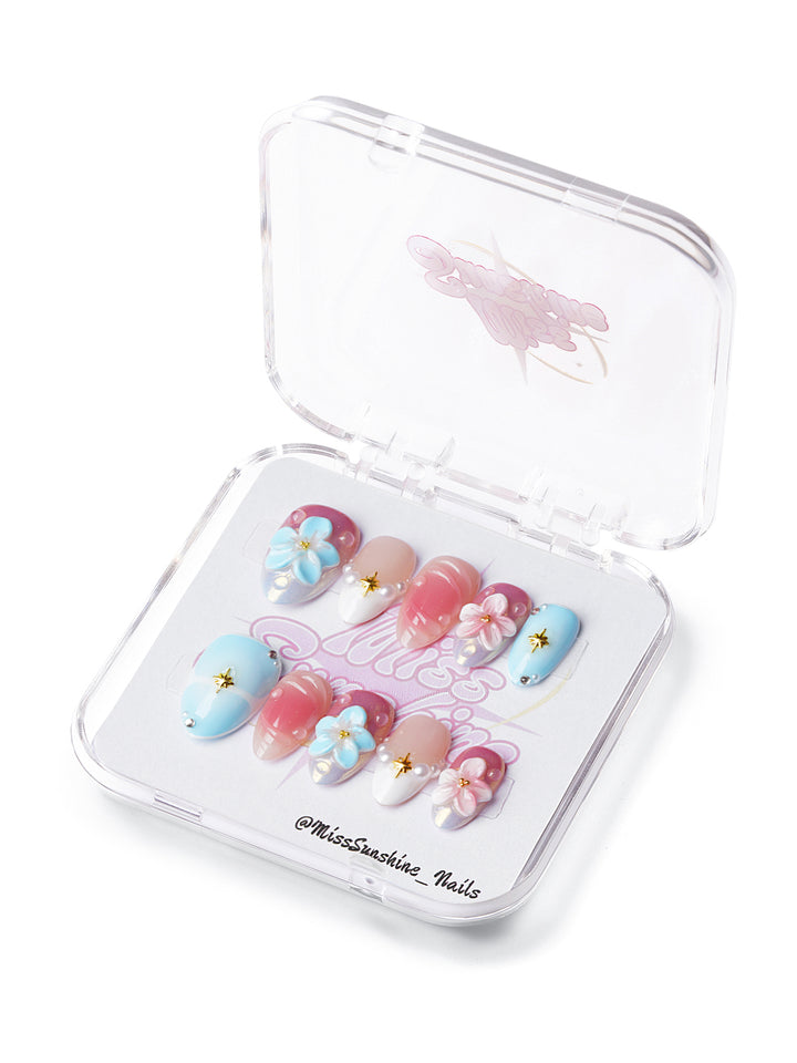 Extra short almond press-on nails in pastel pink and blue with 3D flowers, pearls, and golden star accents