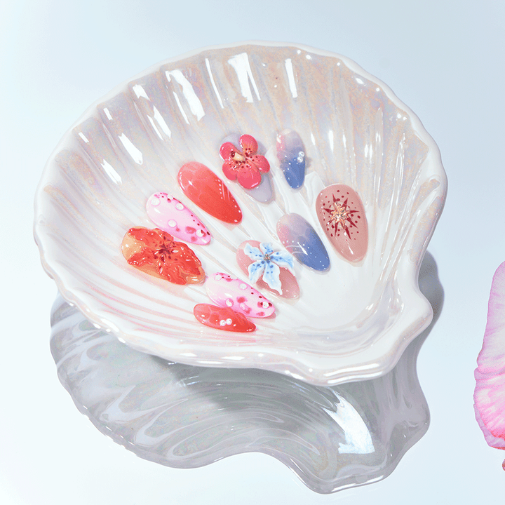 Short almond press-on nails with floral art, coral accents, and ombré summer tones.