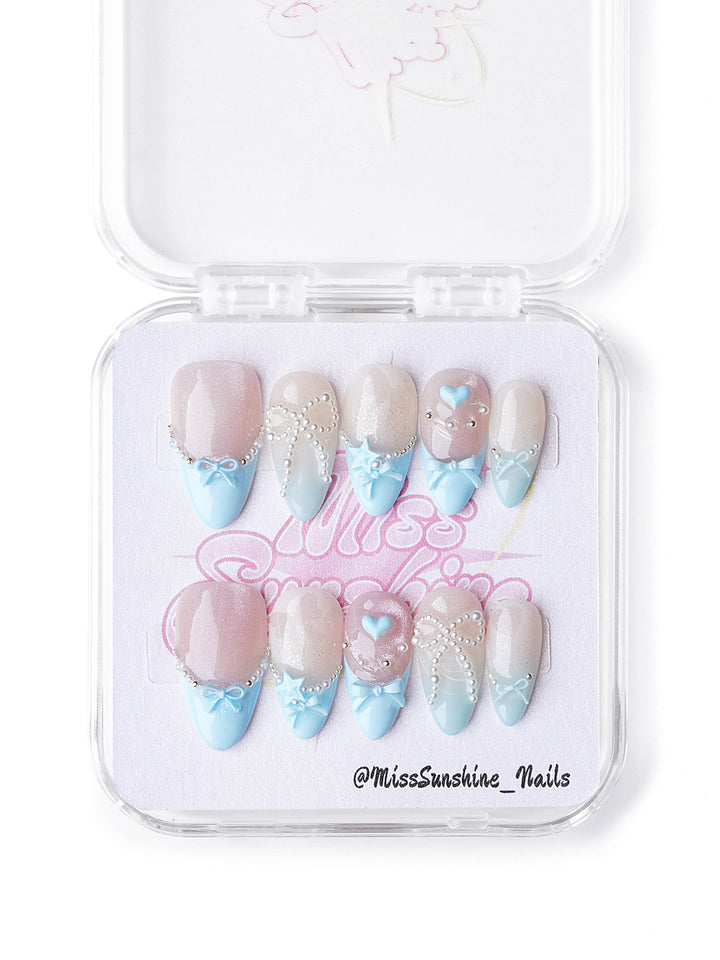 Short almond pastel winter nails with bows, pearls, and nude-to-blue gradients
