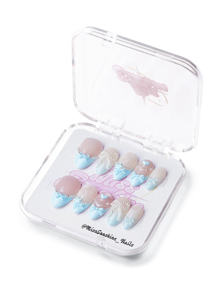 Sweet Bow short almond press-on nails with nude shimmer, baby blue French tips, pearls, and 3D bow accents