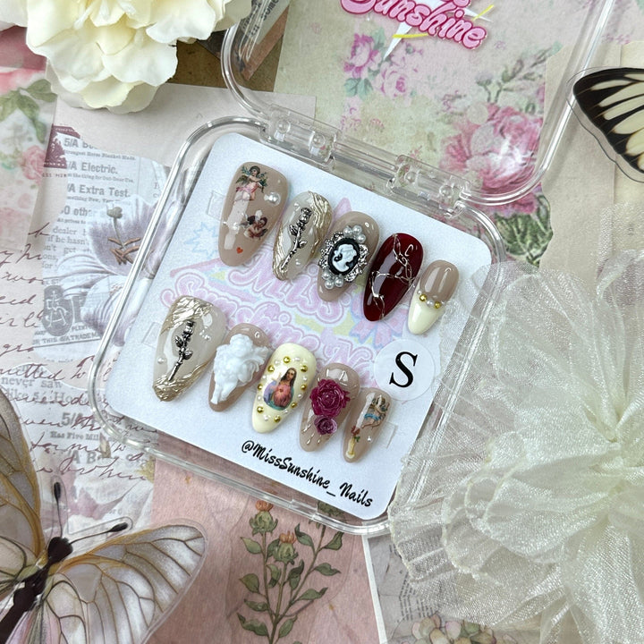 Artistic nail set featuring gold leaves, pearls, and hand-painted portraits on press-ons
